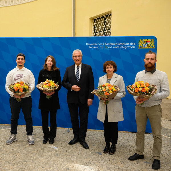 Gruppenfoto mit Innenminister Joachim Herrmann und den vier Eingebürgerten mit Blumensträußen