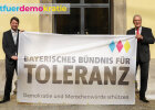Kirchner und Herrmann halten ein Banner des Bayerischen Bündnis für Toleranz "Demokratie und Menschenwürde schützen"
